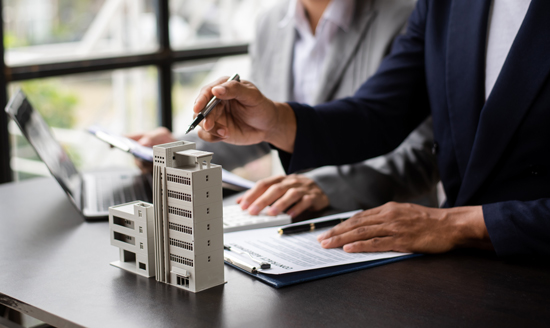 Personne montrant une maquette d'immeuble avec un stylo